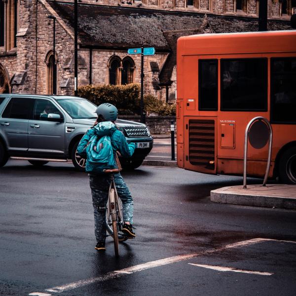 Child on bike trying to cross a busy road, traffic in background