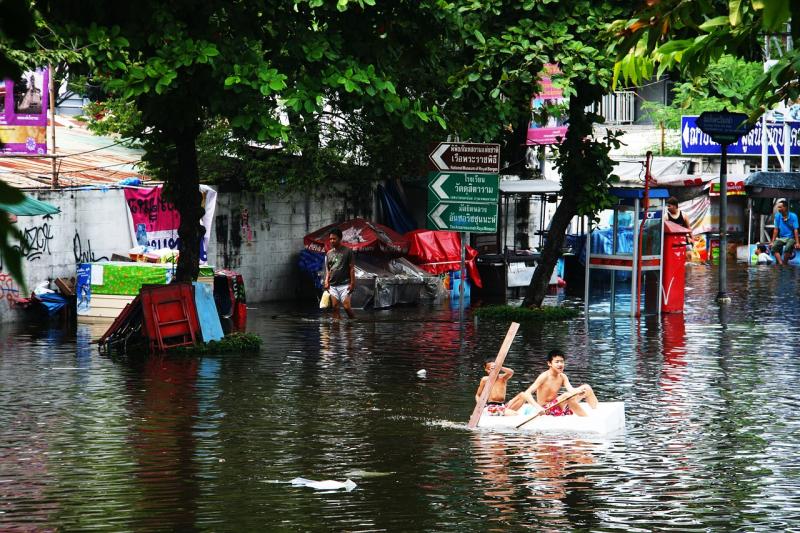 boys paddling raft in flooded streets