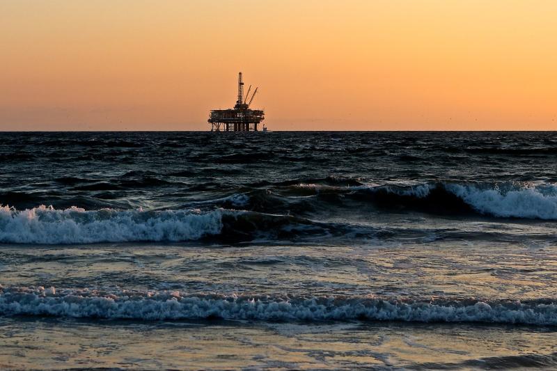 Oil rig at sea silhouetted against horizon