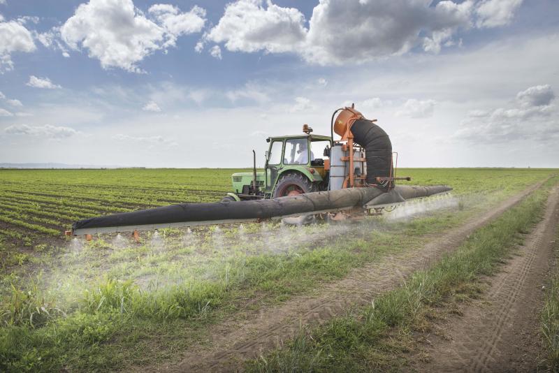 tractor and sprayer spraying pesticides on field