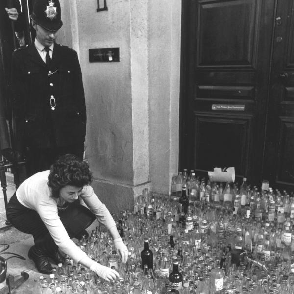 Black & white photo of 1971 bottle dump outside Schweppes HQ, policeman in background