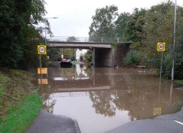 Flooded road and pavement under road bridge, Heol Las in Swansea, October 2021