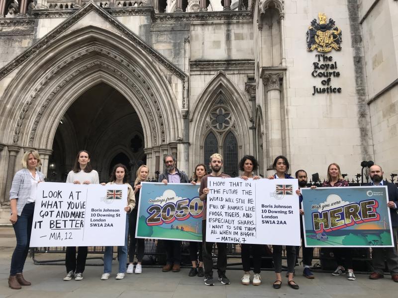 People demonstrating with giant postcards outside the Royal Courts of Justice