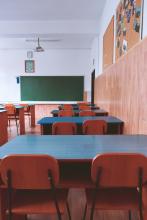 An empty school classroom with desks and a blackboard