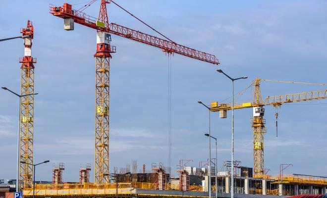 Building the lifts on big construction site with cranes