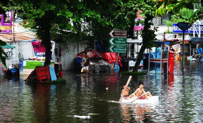 boys paddling raft in flooded streets