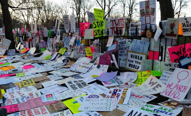 Placards from women's march lined up against fence