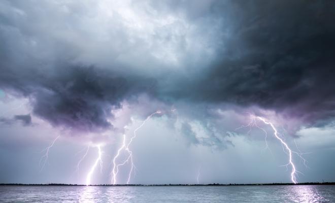 Lightning strike over calm sea, stormy clouds