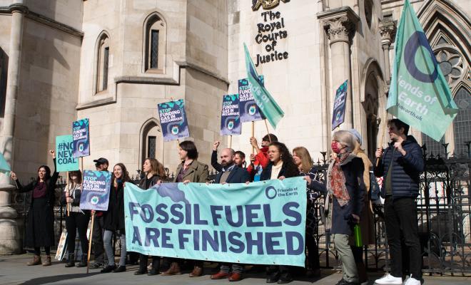Campaigners stand outside the Royal Courts of Justice with placards