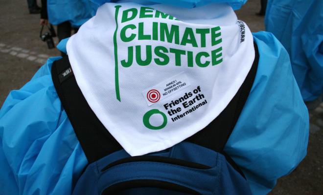 Rearview of activist wearing a banner saying demand Climate Justice