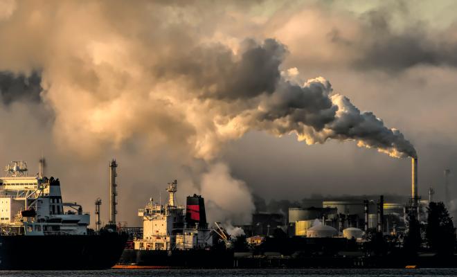 Industrial pollution, smoking chimneys, ship loading in foreground