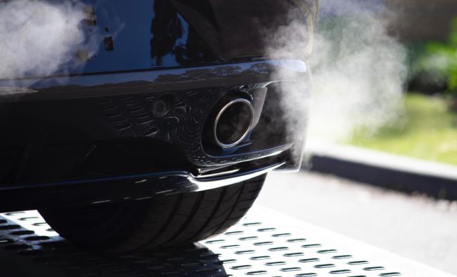 The rear end of a car emitting fumes from its exhaust pipe